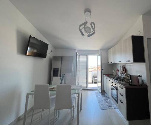 uma cozinha com uma mesa de vidro e cadeiras brancas em Residence Borghi em Scalea