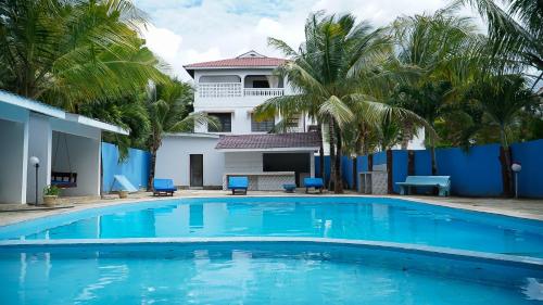 a swimming pool in front of a house with palm trees at Jameela House, 3 mins to Diani Beach, Spa, Laundry, Transport & Catering Available in Ukunda