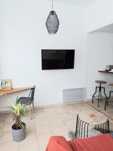 een woonkamer met een tv aan een witte muur bij Appart confort#1, centre-ville, Gare à pieds proche commodités calme in Maubeuge