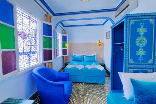 ein Schlafzimmer mit einem blauen Bett und einem blauen Stuhl in der Unterkunft Riad Hôtel Essaouira in Marrakesch