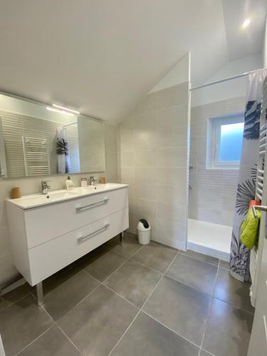 une salle de bain blanche avec un lavabo et une douche dans l'établissement Duo des Falaises, à Octeville-sur-Mer