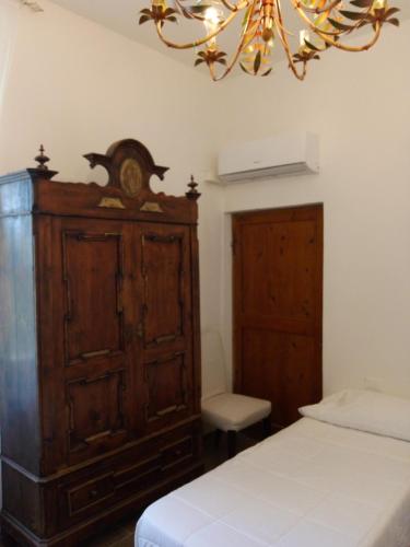 a bedroom with a wooden cabinet and a chandelier at Notte Rosa Suites & Relax in Fornovo di Taro