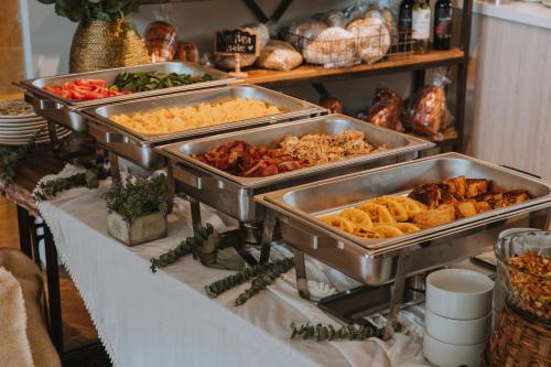a buffet with several trays of food on a table at Travelers Rio Verde Living Suites in Rionegro