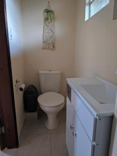 a bathroom with a white toilet and a sink at Sobrado da Vila, 1km Centro, ideal Trabalho e Passeio in Morretes