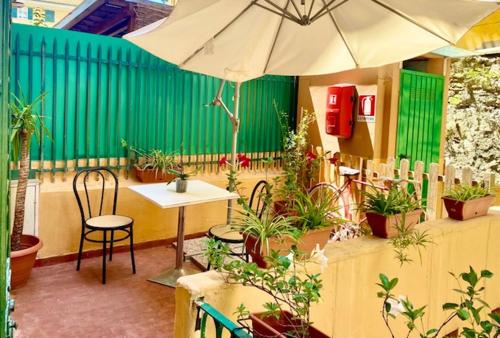 a patio with a table and an umbrella and potted plants at Actor Hotel in Genova