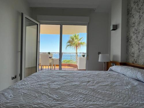 MI CAPRICHO, Beach Front Apartment P.14 3ºB في ميخاس كوستا: غرفة نوم مع سرير وإطلالة على المحيط