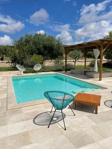 a swimming pool with a chair and a table and a bench at Trullo Matilde in Martina Franca