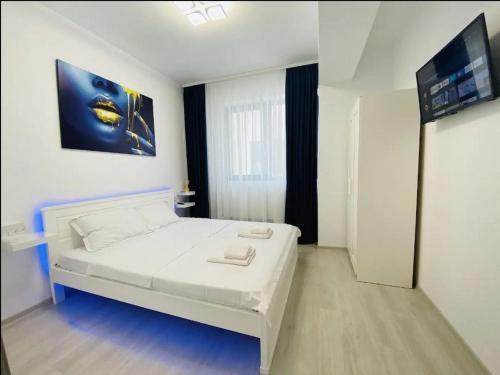 a bedroom with a white bed and a flat screen tv at Alezzi Yacht Apartments with Sea View Near the Beach in Năvodari