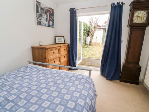 a bedroom with a bed and a window with a clock at Fair Mead Cottage in Saltash