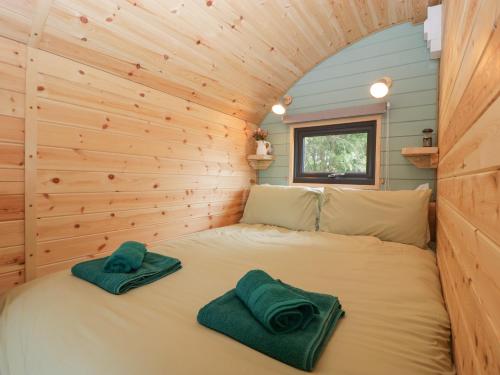 ein Bett in einem winzigen Haus mit zwei Handtüchern darauf in der Unterkunft Dew Pond in Blagdon