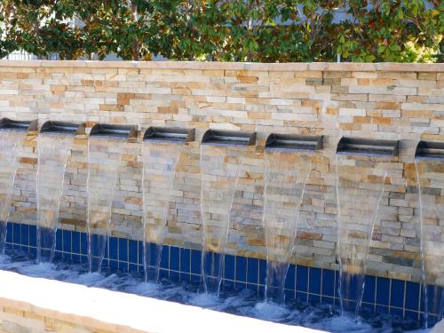 a water fountain in front of a brick wall at The Nest Hotel Palo Alto in Palo Alto