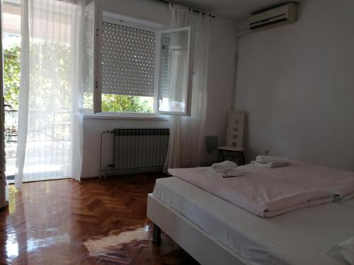 a white bedroom with a bed and a window at Apartment Selce 2381d in Selce