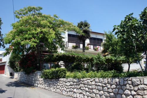 a building with a stone retaining wall and trees at Double Room Novi Vinodolski 2350a in Novi Vinodolski