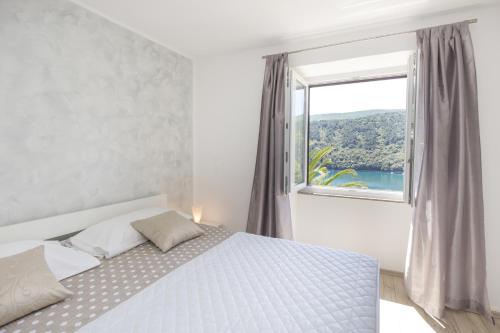 a bedroom with a bed and a large window at Apartments by the sea Duga Luka - Prtlog, Labin - 2358 in Drenje
