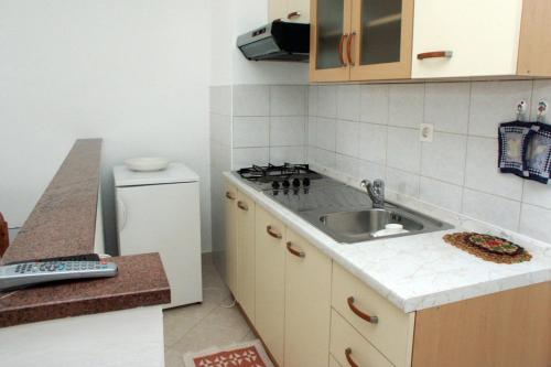 a small kitchen with a sink and a refrigerator at Apartments by the sea Duga Luka - Prtlog, Labin - 2367 in Drenje