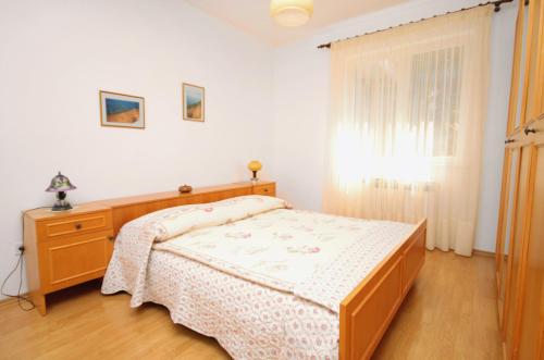 a bedroom with a bed and a dresser and a window at Apartment Rabac 2340a in Rabac