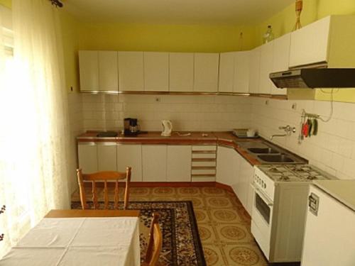 uma cozinha com armários brancos, uma mesa e um fogão em Apartments by the sea Sveti Juraj, Senj - 2399 em Sveti Juraj