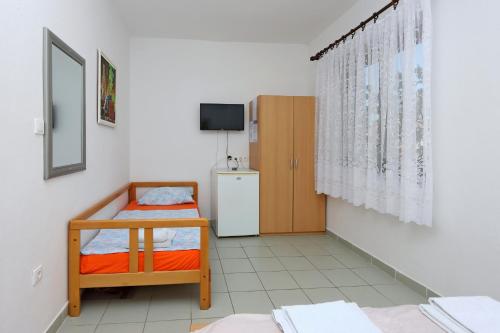 Kleines Zimmer mit 2 Betten und einem Kühlschrank. in der Unterkunft Triple Room Selce 2362c in Selce