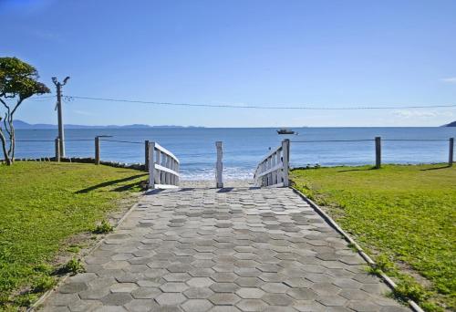 a stone pathway leading to the ocean with a fence at Monte Libano Apart Hotel in Florianópolis