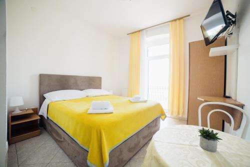 a hotel room with a bed with a yellow blanket at Studio Selce 2364c in Selce