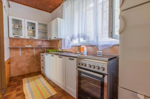 a kitchen with white cabinets and a stove and a window at Apartment Selce 2381a in Selce