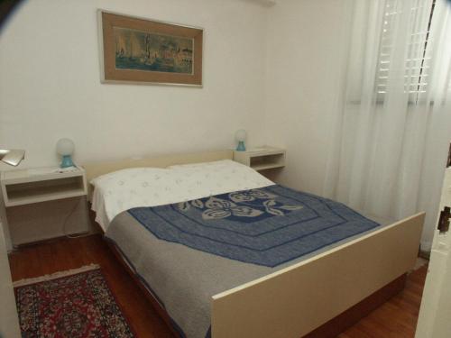 a small bedroom with a bed with a blue blanket at Apartment Selce 2372c in Selce