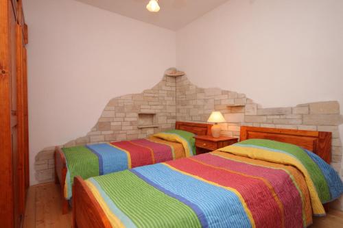 sypialnia z 2 łóżkami i kolorowymi kocami w obiekcie Family friendly apartments with a swimming pool Manjadvorci, Marcana - 2301 w mieście Barban