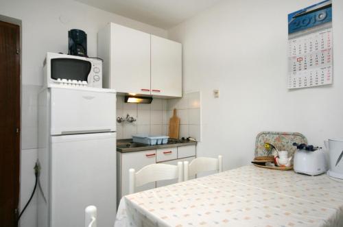 a kitchen with a table and a white refrigerator at Apartments with a parking space Njivice, Krk - 2391 in Njivice