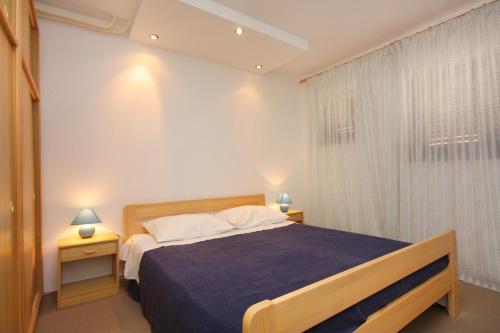 sypialnia z łóżkiem z niebieskim kocem i oknem w obiekcie Apartments with a parking space Njivice, Krk - 2391 w mieście Nijvice