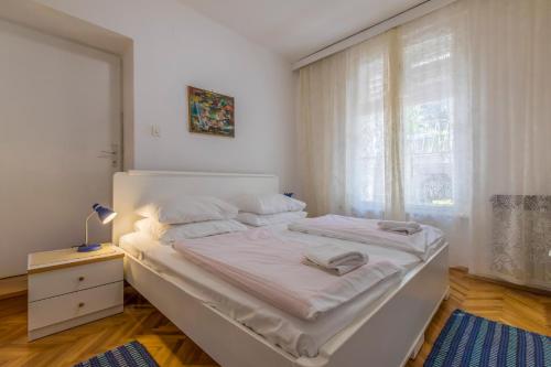 ein weißes Schlafzimmer mit einem Bett und einem Fenster in der Unterkunft Apartments with a parking space Selce, Crikvenica - 2381 in Selce