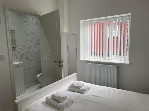 a white bathroom with towels on a bed and a shower at CityBreaks Rooms with Free Parking in Liverpool