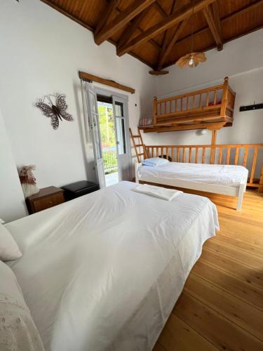 Duas camas brancas num quarto com pisos em madeira em Elios Summer House em Neo Klima