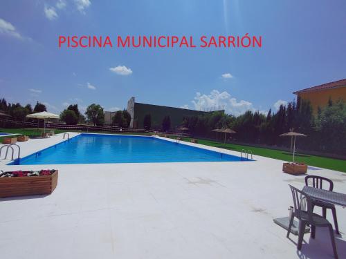 a large swimming pool in a park with chairs and tables at Casa Rural Sarrion in Teruel