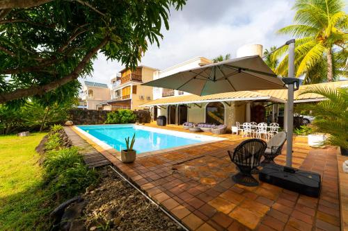 a patio with an umbrella and a swimming pool at Villa Osiris in Flic-en-Flac