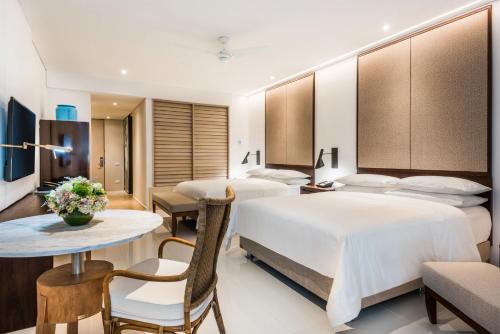 a hotel room with two beds and a table and chairs at Dreams Karibana Cartagena Golf & Spa Resort in Cartagena de Indias
