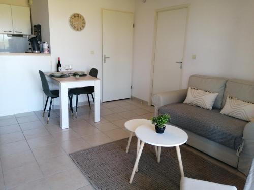 a living room with a couch and a table at Le cocon de Marie,piscine, balcon, parking gratuit, baignoire in Carcassonne