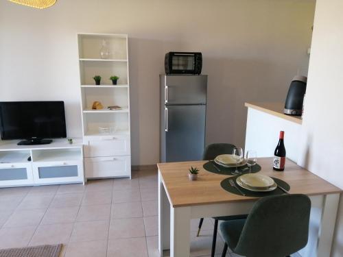 a kitchen with a table and a refrigerator at Le cocon de Marie,piscine, balcon, parking gratuit, baignoire in Carcassonne