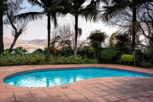 a swimming pool in a yard with palm trees at Vintage Serene Villa in Hartbeespoort