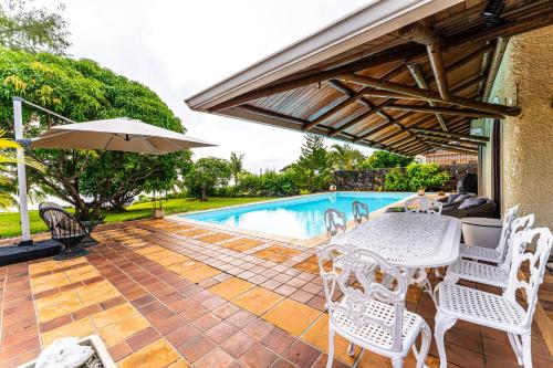a patio with a table and chairs and a pool at Villa Osiris in Flic-en-Flac