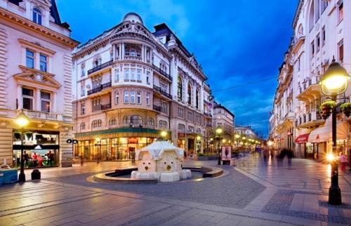 a city street with buildings and a fountain in the middle at Palace Luxury Apartments The Heart of Belgrade in Belgrade