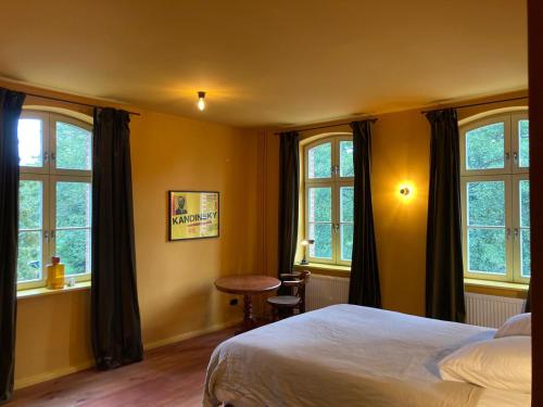 a bedroom with a bed and a table and windows at Hug&Dim im Gasthaus am Finowkanal in Wandlitz