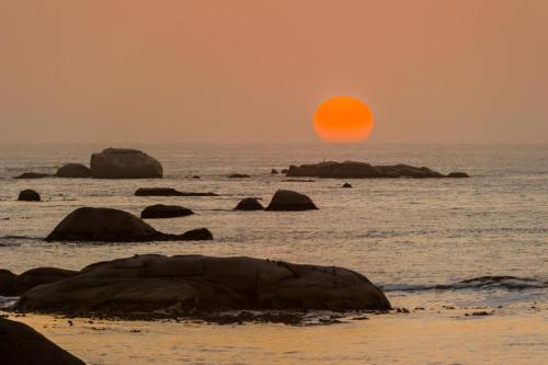 a sunset over the ocean with rocks in the water at The Oystercatchers Haven at Paternoster in Paternoster