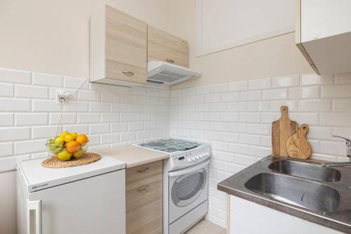 a white kitchen with a sink and a dishwasher at Roomsy Świętojańska in Gdynia