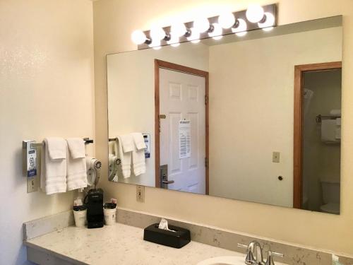 a bathroom with a sink and a large mirror at Travelodge by Wyndham Three Forks in Three Forks