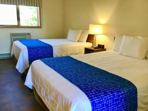 a hotel room with two beds with blue and white sheets at Travelodge by Wyndham Three Forks in Three Forks