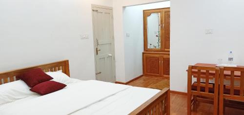 a bedroom with a bed with white sheets and red pillows at Moon Homestay in Santhanpara