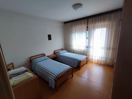 Duas camas num quarto com uma janela em Casa Celeste em Farra dʼAlpago