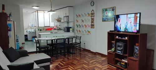 a living room with a tv and a table and a kitchen at Apartamento Marco Airport in Lima