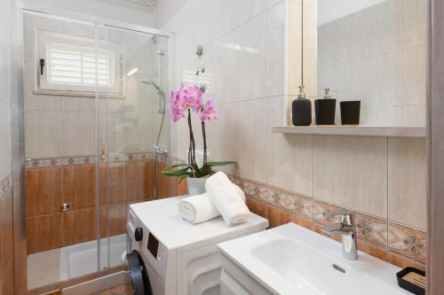 baño con lavabo y jarrón de flores en Marina, en Rabac