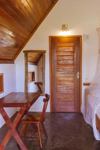 a room with a desk and a bed and a wooden door at Pousada Velho Bateau in Atins